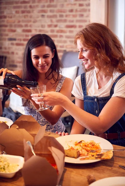 友人と一緒に家でワインとテイクアウトの食事を楽しむ2人の女性 — ストック写真