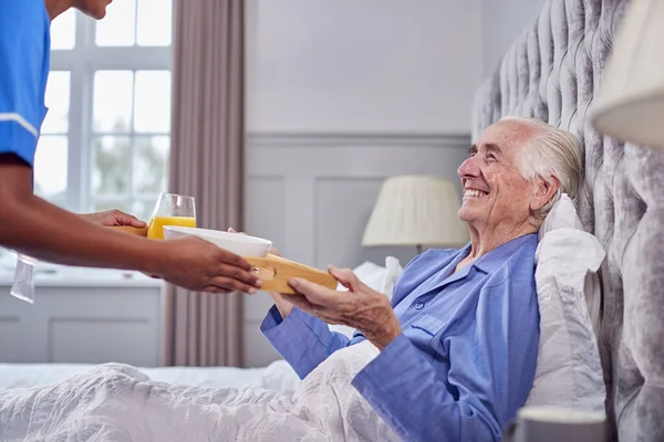 Female Care Worker Uniform Bringing Senior Man Home Breakfast Bed — Stock Fotó