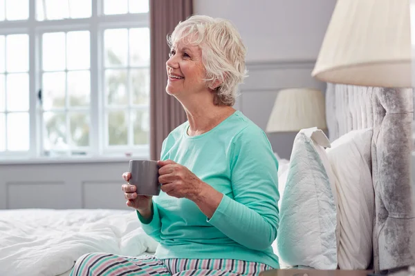 Senior Woman Home Wearing Pyjamas Sitting Bed Having Morning Cup — стоковое фото