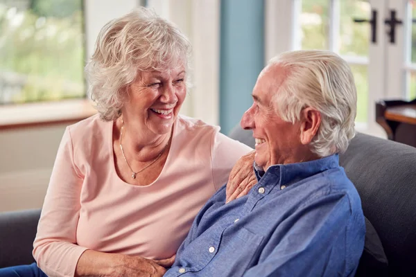 Loving Senior Couple Enjoying Retirement Sitting Sofa Home Talking Laughing — Foto Stock