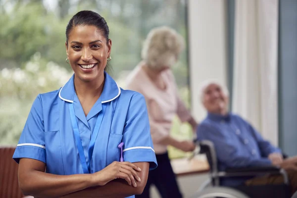 Portrait Of Female Nurse Or Care Worker Making Home Visit To Senior Couple With Man In Wheelchair