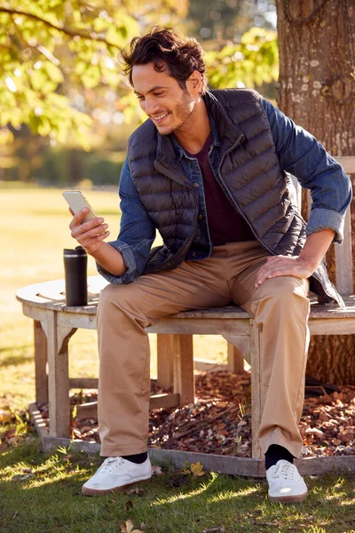 Smiling Man Sitting Bench Autumn Park Using Mobile Phone — Photo