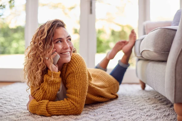 Woman Warm Jumper Lying Floor Home Talking Mobile Phone — Zdjęcie stockowe