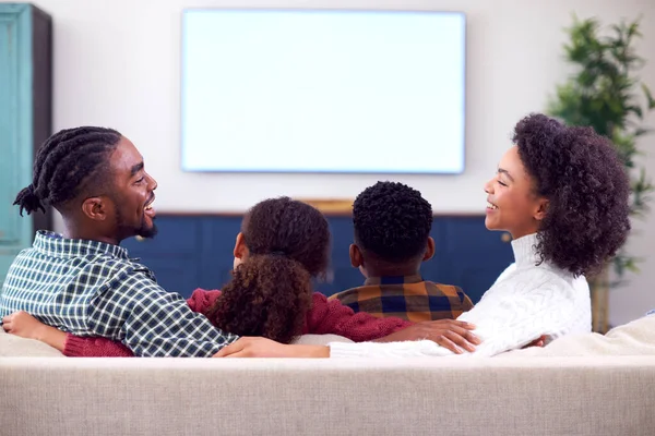 家庭坐在沙发上看电视的后视镜 — 图库照片