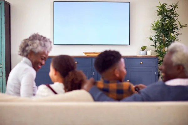 孫と祖父母が自宅でテレビで映画を見てソファに座っている様子 — ストック写真