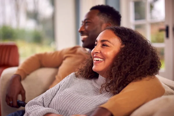 Uśmiechnięta Para Siedzi Kanapie Domu Oglądając Razem Telewizję — Zdjęcie stockowe