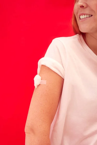 注射や赤の背景に対してワクチン接種後に腕にテープウールを持つ女性 — ストック写真
