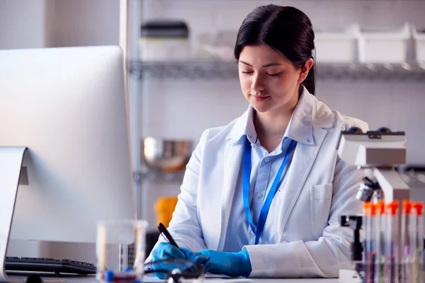 Female Lab Worker Wearing White Coat Recording Test Results Computer — Zdjęcie stockowe