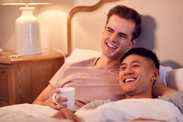 Loving Same Sex Male Couple Lying Bed Home Watching Together — стоковое фото