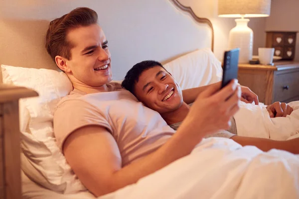 Loving Same Sex Male Couple Lying Bed Home Looking Social — стоковое фото