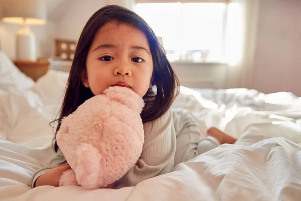 Menina Jovem Sentada Cama Vestindo Pijama Casa Abraçando Brinquedo Macio — Fotografia de Stock