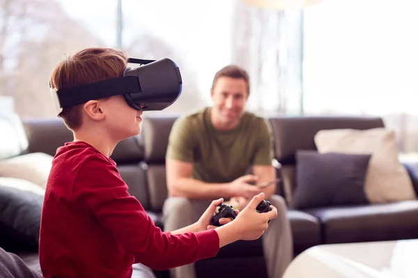 爸爸看儿子戴着虚拟现实耳机在家里玩电脑游戏 — 图库照片