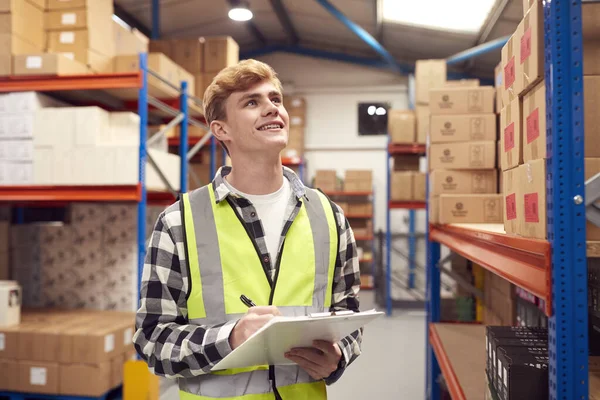 Male Intern Working Warehouse Checking Stock Shelves Using Clipboard — Stock Photo, Image