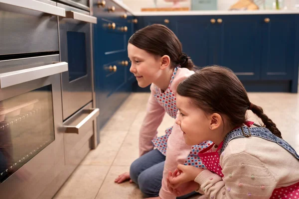Two Girls Waiting Cupcakes Bake Looking Oven Kitchen Home Together — Stock Photo, Image