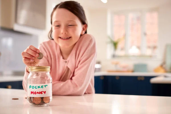Girl Saving Money Jar Labelled Pocket Money Kitchen Counter Home — Stock Photo, Image