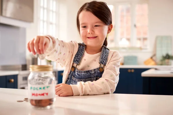 Girl Saving Money Jar Labelled Pocket Money Kitchen Counter Home — Stockfoto