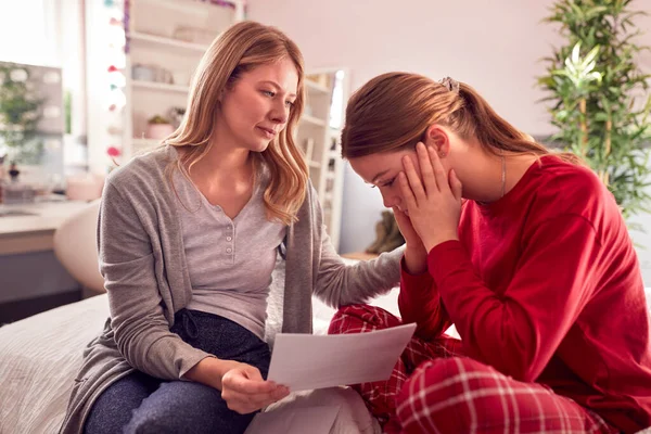 Disappointed Teenage Daughter Wearing Pyjamas Looking School Exam Report Mother — Stok fotoğraf