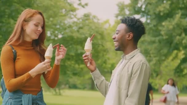 一对年轻夫妇在公园里散步 一起吃冰淇淋 而那个女人却不小心把冰淇淋扔了下来 动作缓慢 — 图库视频影像