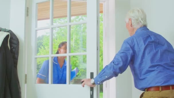 老年男子在家里用步行架招呼着身着制服的女护理人员慢吞吞地开着门 — 图库视频影像