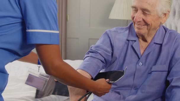 Zbliżenie Seniorem Domu Łóżku Mając Ciśnienie Krwi Zmierzone Przez Opiekunkę — Wideo stockowe