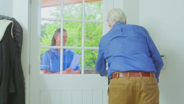 老人ホームで使用して歩行棒挨拶女性介護労働者で制服でドア 遅い動きで撮影 — ストック動画