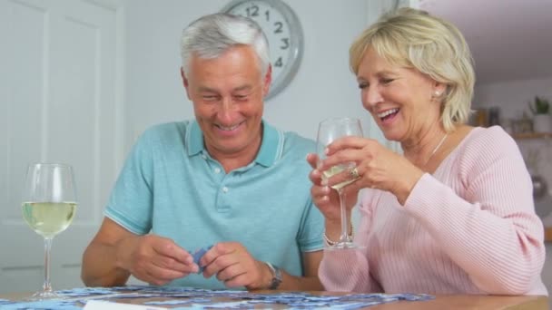 上了年纪的退休夫妇一起坐在桌旁喝酒 一起做拼图游戏 动作缓慢 — 图库视频影像