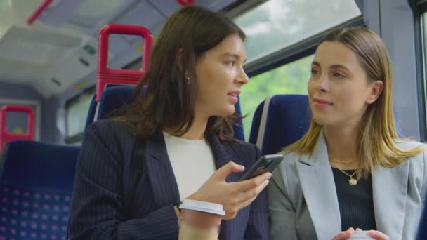 Two Businesswomen Takeaway Coffees Commuting Work Train Looking Mobile Phone — Stok video