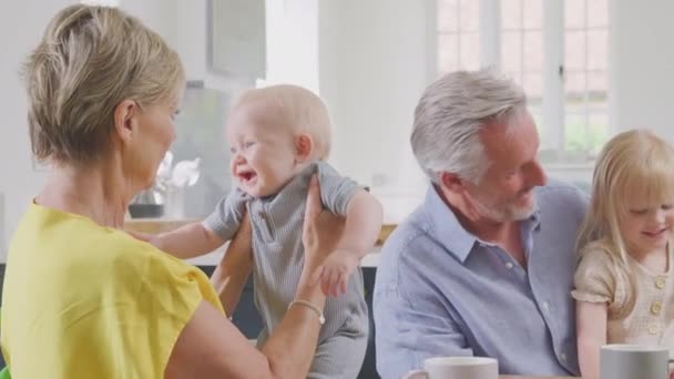 Isovanhemmat Huolehtivat Lapsenlapsesta Suutelevat Lapsenlasta Keittiön Pöydässä Ammuttu Hidastettuna — kuvapankkivideo