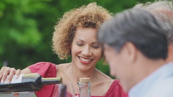 Mulher Enchendo Copo Vinho Festa Bebidas Para Amigos Seniores Jardim — Vídeo de Stock