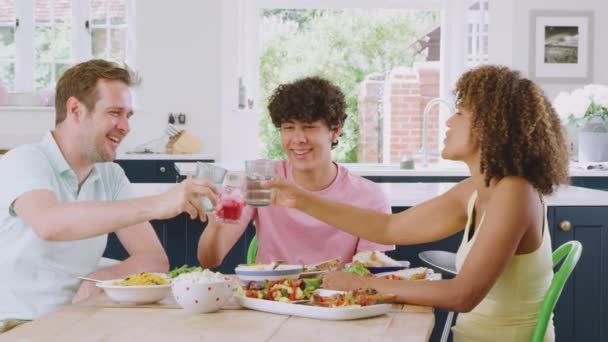 十几岁的儿子 与多种族的父母一起坐在厨房的桌子旁 一起吃着健康的家庭食品 动作缓慢 — 图库视频影像
