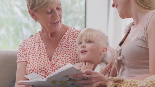 Εγγονή Καμηλοπάρδαλη Παιχνίδι Κάθεται Στον Καναπέ Γιαγιά Και Μητέρα Ανάγνωση — Αρχείο Βίντεο