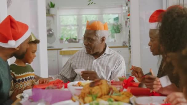 Multi Generation Family Paper Hats Reading Christmas Cracker Jokes Whilst — Stock Video