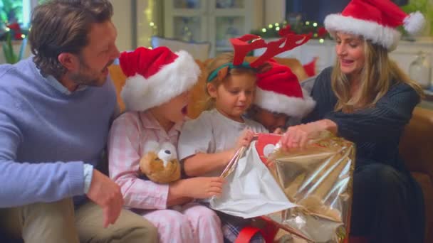 Family Sitting Sofa Home Wearing Santa Hats Children Holding Christmas — Stock Video