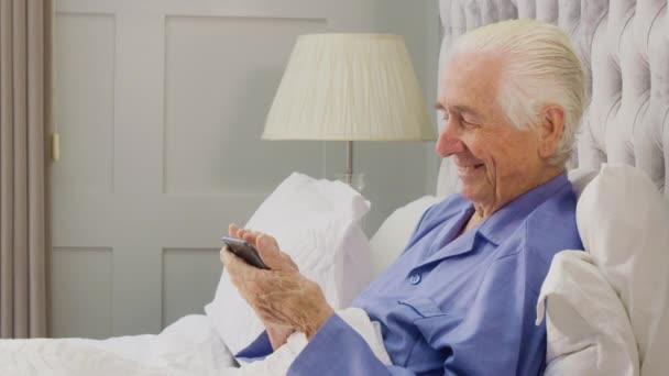 Senior Man Home Wearing Pyjamas Bed Using Mobile Phone Shot — Wideo stockowe