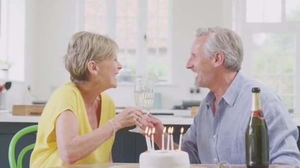 Retired Couple Celebrating Birthday Cake Opening Bottle Champagne Home Together — Vídeo de Stock