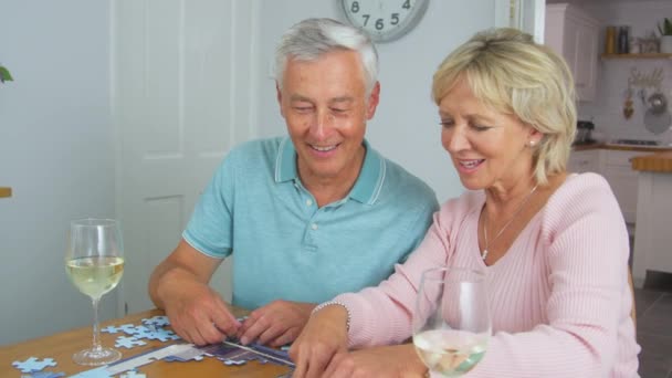 上了年纪的退休夫妇一起坐在桌旁喝酒 一起做拼图游戏 动作缓慢 — 图库视频影像