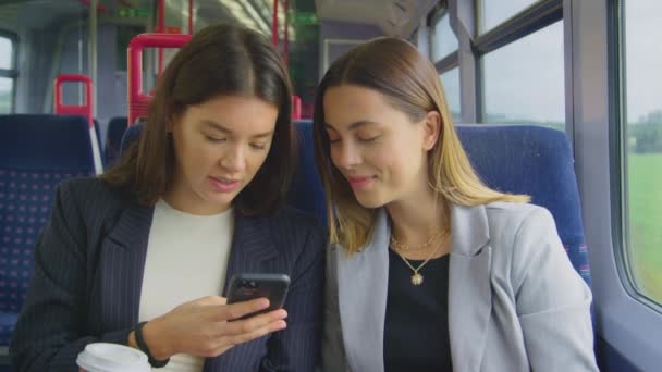Two Businesswomen Takeaway Coffees Commuting Work Train Looking Mobile Phone — Stok video