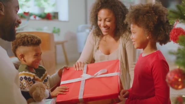 Girl Unwrapping Present Family Exchange Gifts Christmas Tree Home Shot — Vídeo de Stock