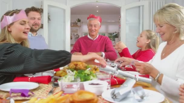 多代家庭一起拉着圣诞饼干 然后戴上纸帽 一起在家里吃饭 动作缓慢 — 图库视频影像