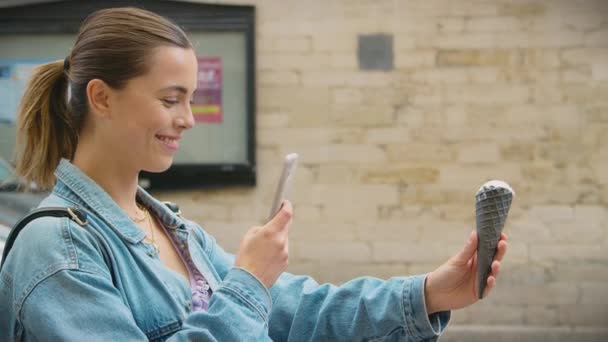 若い女性がソーシャルメディアに投稿する携帯電話でアイスクリームコーンの写真を撮る スローモーションで撮影 — ストック動画