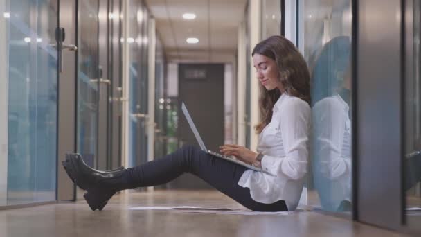 Jovem Empresária Sentada Chão Corredor Escritório Moderno Trabalhando Laptop Filmada — Vídeo de Stock