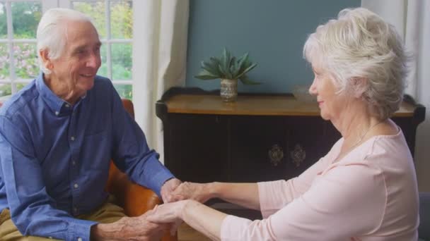 Loving Senior Couple Holding Hands Sitting Sofa Home Talking Laughing — Vídeo de Stock