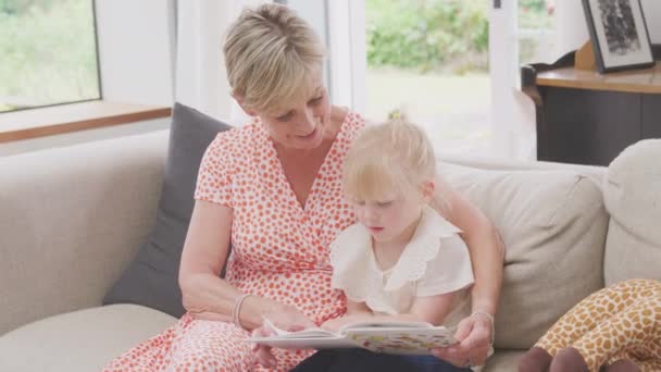 Granddaughter Sitting Sofa Grandmother Reading Story Book Together Shot Slow — 图库视频影像