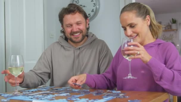 情侣们坐在桌旁 喝着酒杯一起做拼图游戏 动作缓慢 — 图库视频影像