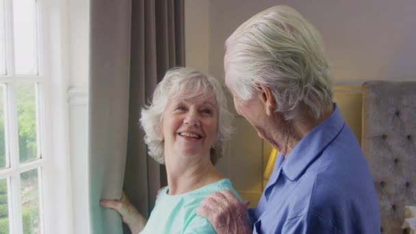 Χαμογελαστό Ζευγάρι Ηλικιωμένων Στο Σπίτι Φορώντας Πιτζάμες Τραβώντας Κουρτίνες Στην — Αρχείο Βίντεο