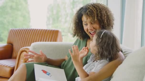 妈妈和女儿坐在沙发上笑着一起看书 动作缓慢 — 图库视频影像