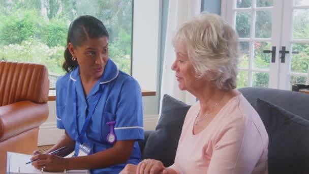 Senior Kvinna Hemma Pratar Med Kvinnliga Sjuksköterska Eller Vårdpersonal Uniform — Stockvideo