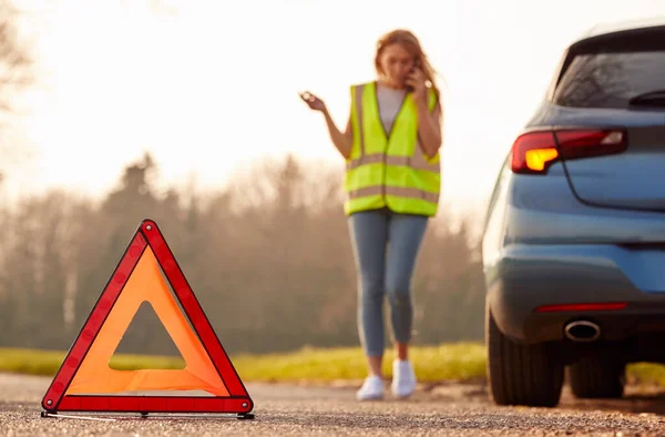 Hazard Warning Triangle Sign For Car Breakdown On Road With Woman Calling For Help