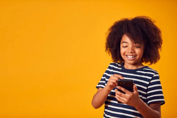 Retrato Estudio Niño Joven Usando Teléfono Móvil Contra Fondo Amarillo —  Fotos de Stock