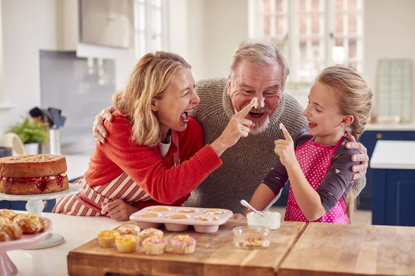 Großeltern Mit Enkelin Beim Cupcakes Backen Und Sahnehäubchen Auf Der — Stockfoto